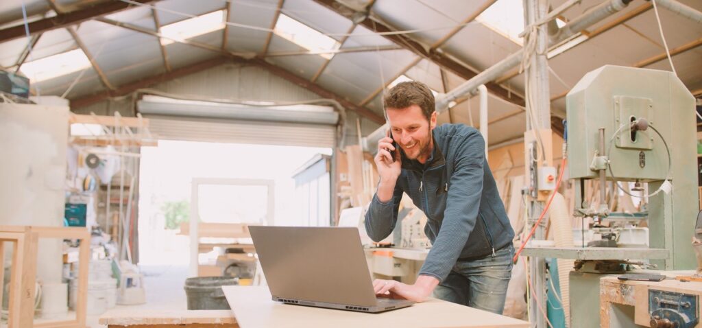 carpenter working in woodwork workshop talking on phone