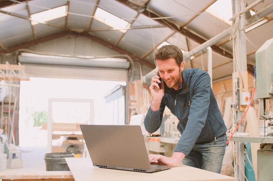 carpenter working in woodwork workshop talking on phone