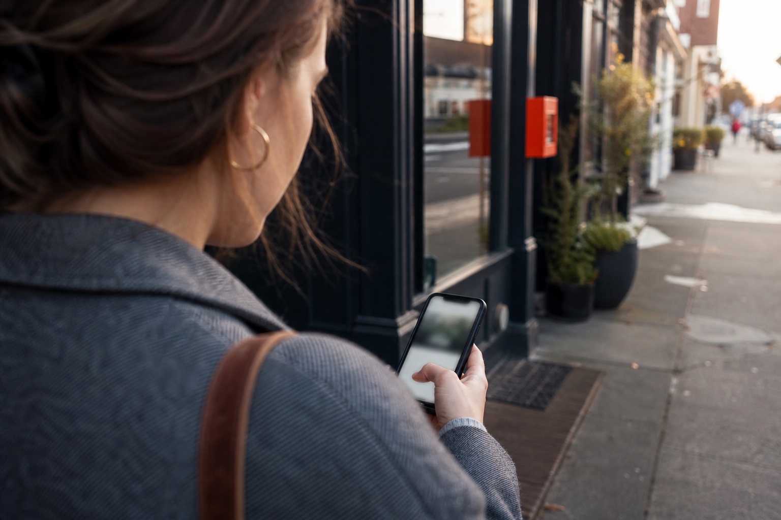 Person testing a service-business website on a mobile phone outside the business location.